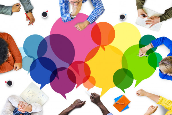 aerial view of people in conversation at a table covered in multi-coloured speech bubbles